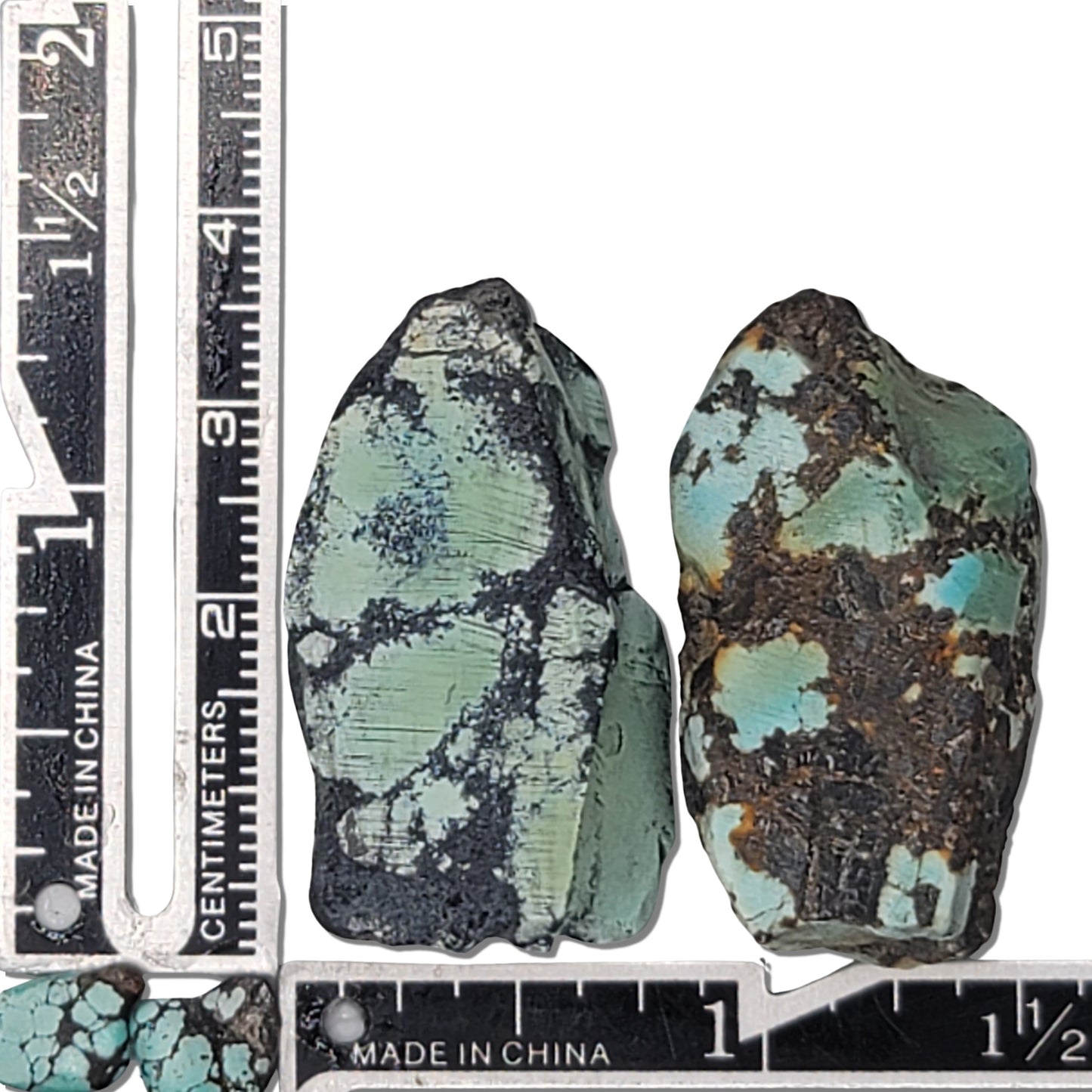 A 27-gram pair of natural turquoise stones with vibrant greenish-blue hues and striking black matrix. Ideal for creating unique jewelry or as a raw collectible, available at www.naturalturquoise.com.