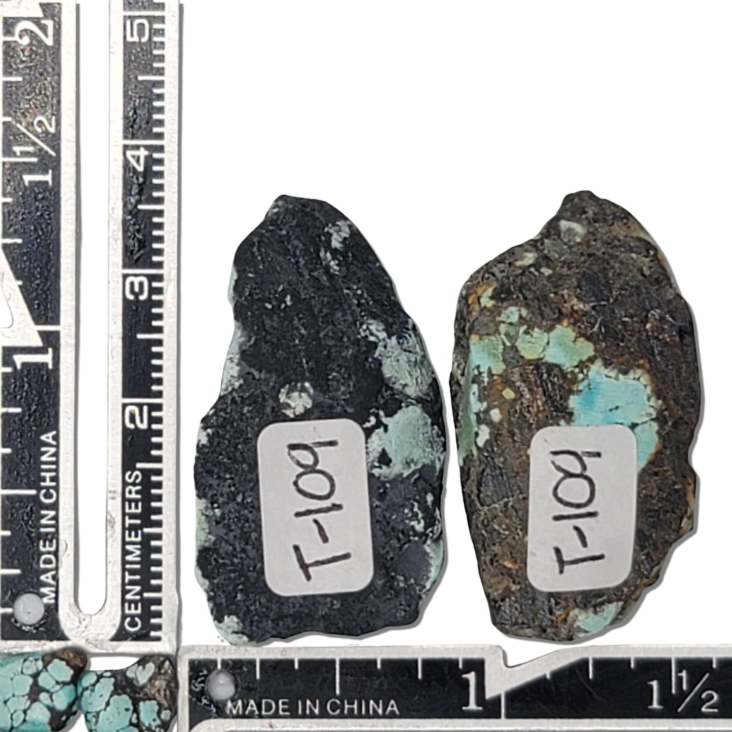 A 27-gram pair of natural turquoise stones with vibrant greenish-blue hues and striking black matrix. Ideal for creating unique jewelry or as a raw collectible, available at www.naturalturquoise.com.