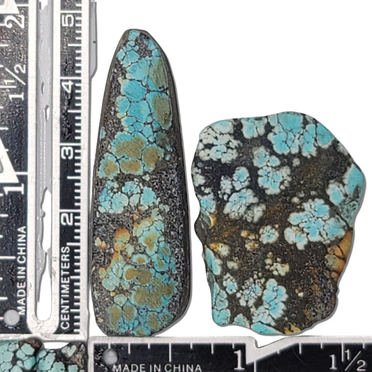 A pair of natural turquoise stones weighing 21 grams, featuring vibrant blue tones with golden and dark matrix patterns. The stones measure approximately 5 cm x 2 cm and 3.5 cm x 3 cm, displayed with a ruler for scale. Available for purchase at www.naturalturquoise.com, ideal for lapidary and jewelry projects.