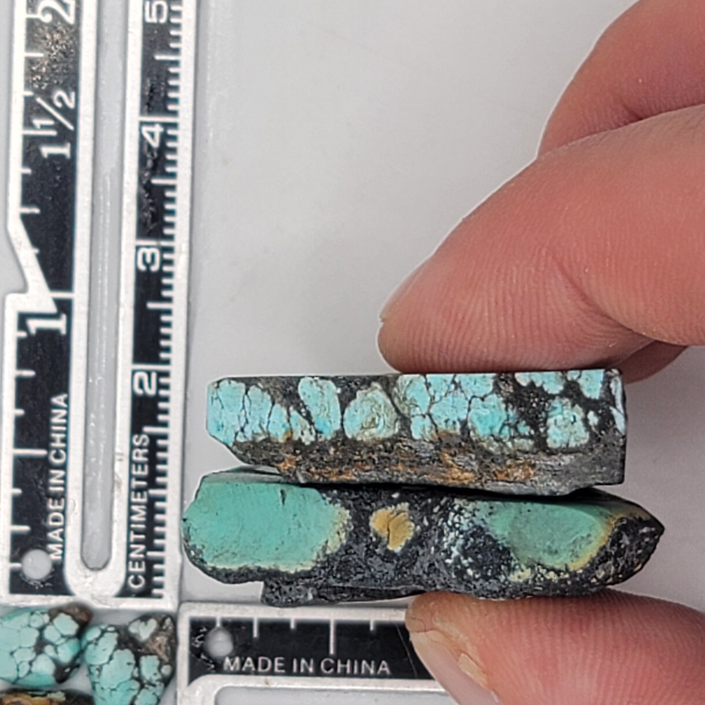 A natural turquoise stone pair weighing 22 grams, featuring rich green and vibrant blue hues with bold dark matrix patterns. The stones measure approximately 4.5 cm x 3.2 cm and 4 cm x 2.8 cm, displayed with a ruler for scale. Available for purchase at www.naturalturquoise.com, perfect for lapidary and jewelry projects.